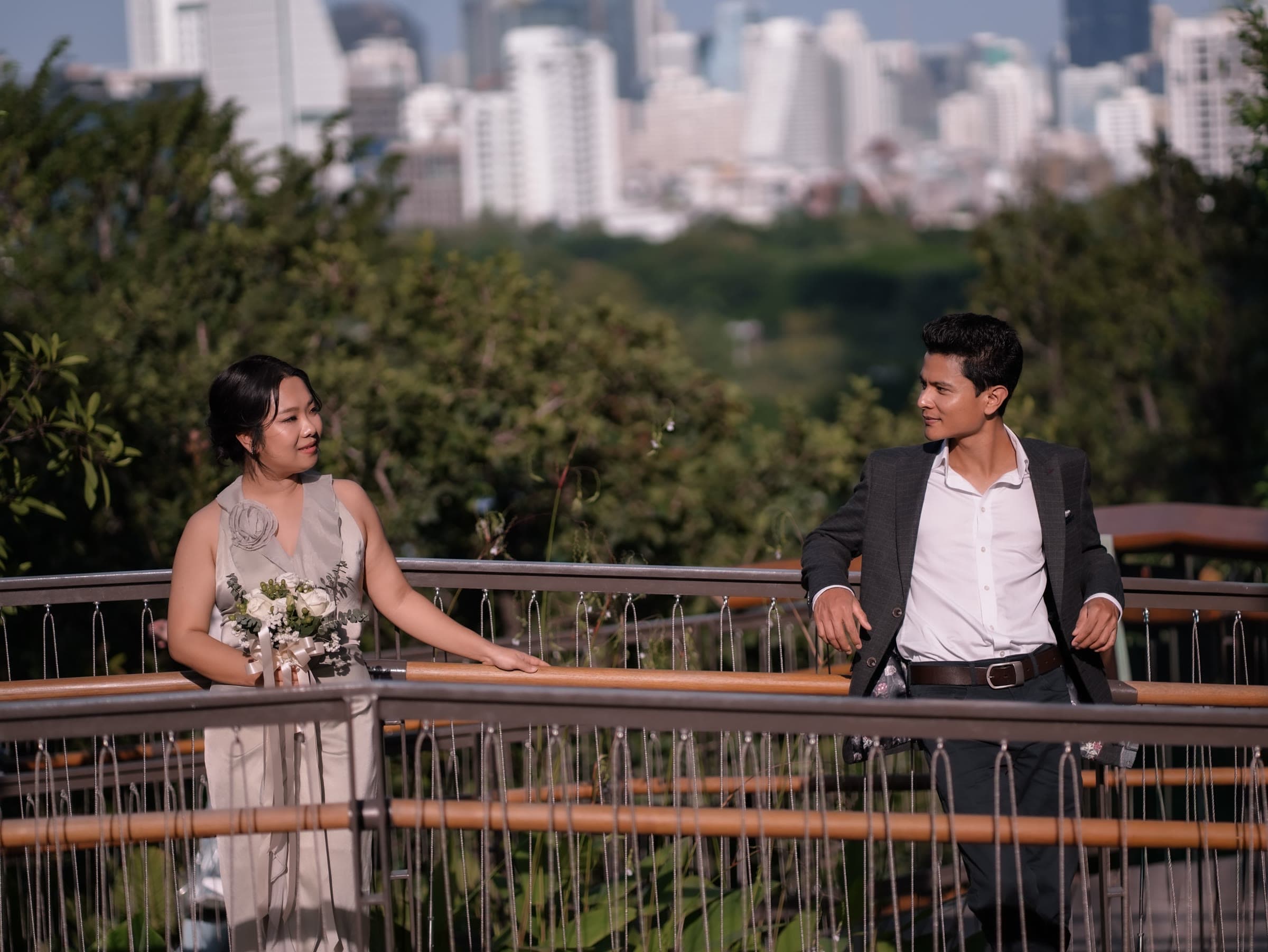 Dr Thet Naing Htun and Dr Thet Su Mon on a bridge with the Bangkok skyline behind them